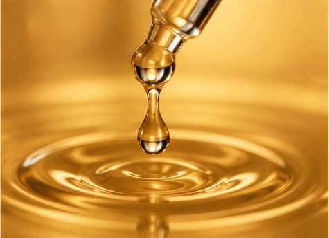 A golden oil drop above a reflective surface